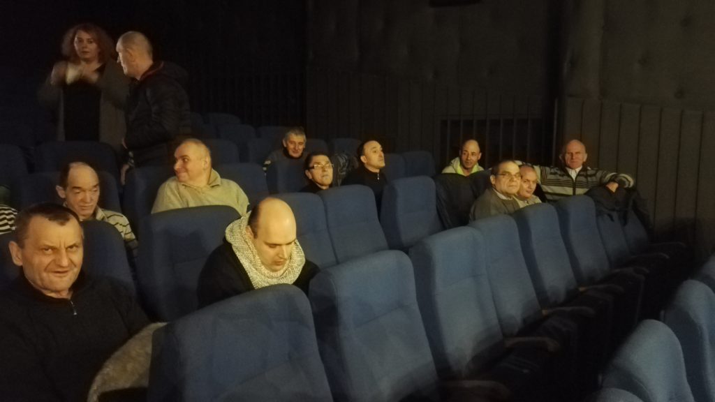 Mieszkańcy Domu Pomocy Społecznej w Chojnie siedzący na widowni w kinie.