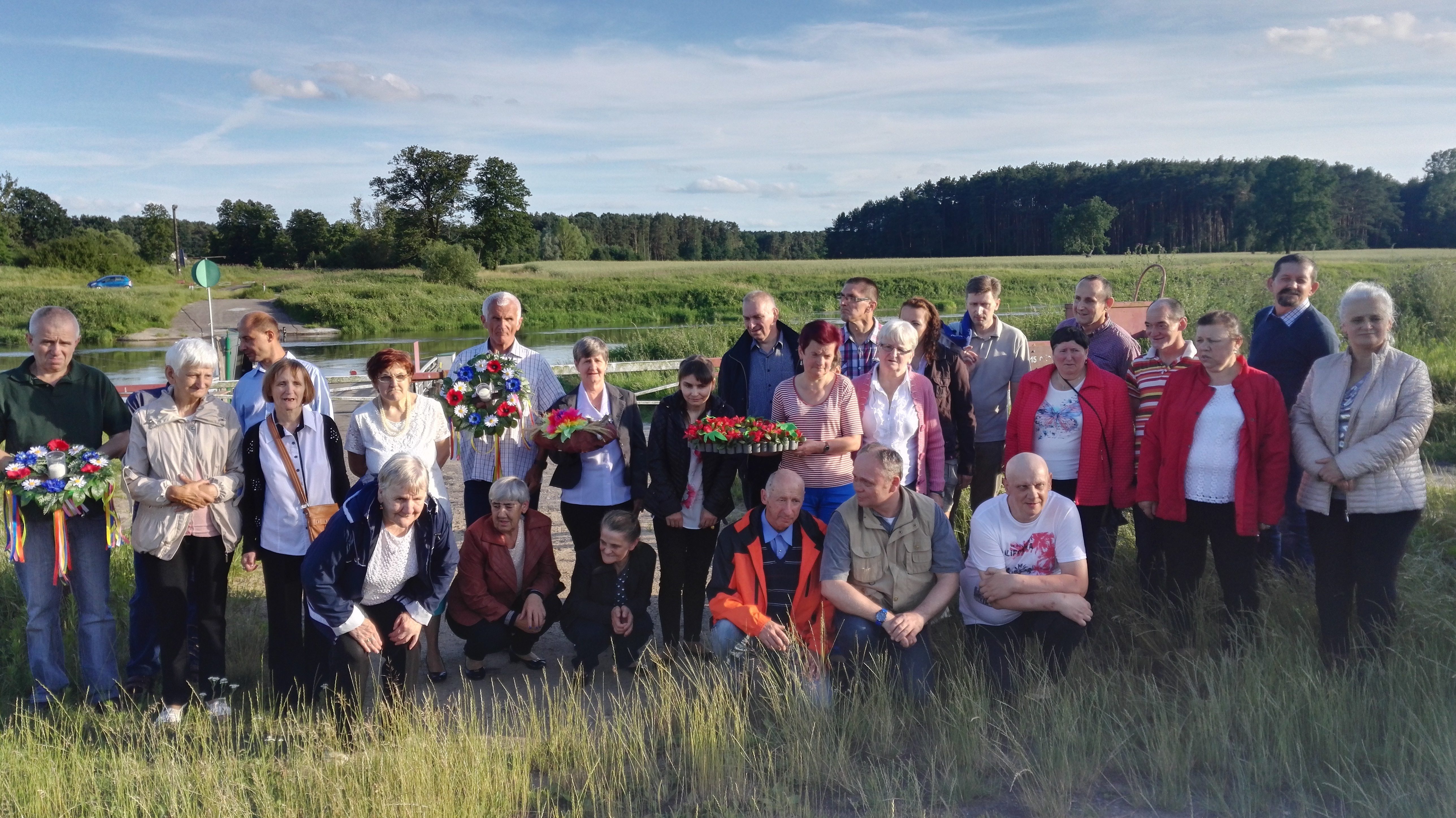 Mieszkańcy Domów Pomocy Społecznej z Chojna, Wielenia, Trzcianki, Nowej Wsi oraz Chrzypska pozują do zdjęcia trzymając wianki przed rzeką Wartą.