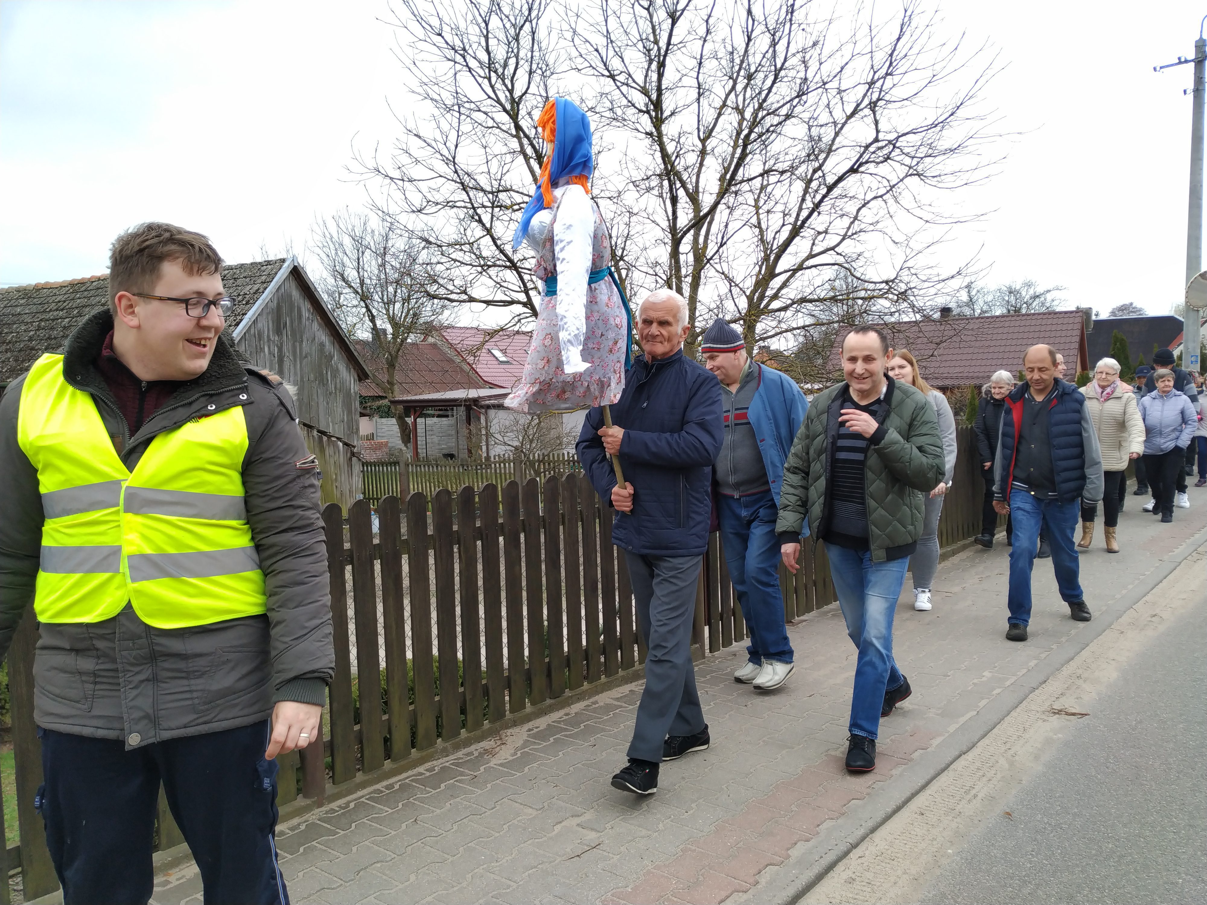 Mieszkańcy Domów Pomocy Społecznej w Chojnie i Nowej Wsi idą w parach po chodniku z kukłami Marzanny.