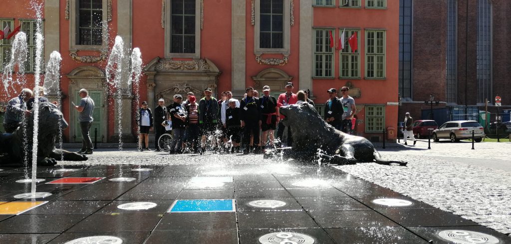 Mieszkańcy Domu Pomocy Społecznej w Chojnie stoją przy fontannie i rzeźbach gdańskich lwów.